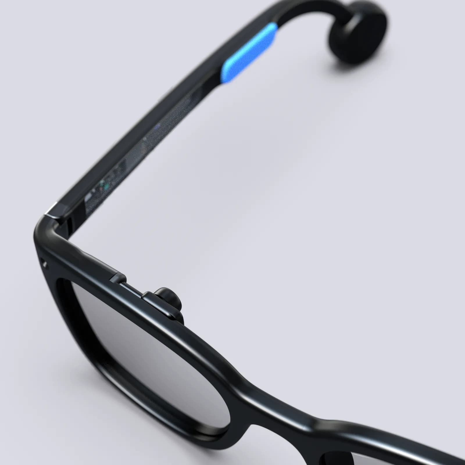 Gafas Brilliant Labs Halo en negro, primer plano de la bisagra de la patilla, con una franja azul iluminada y un botón pequeño.