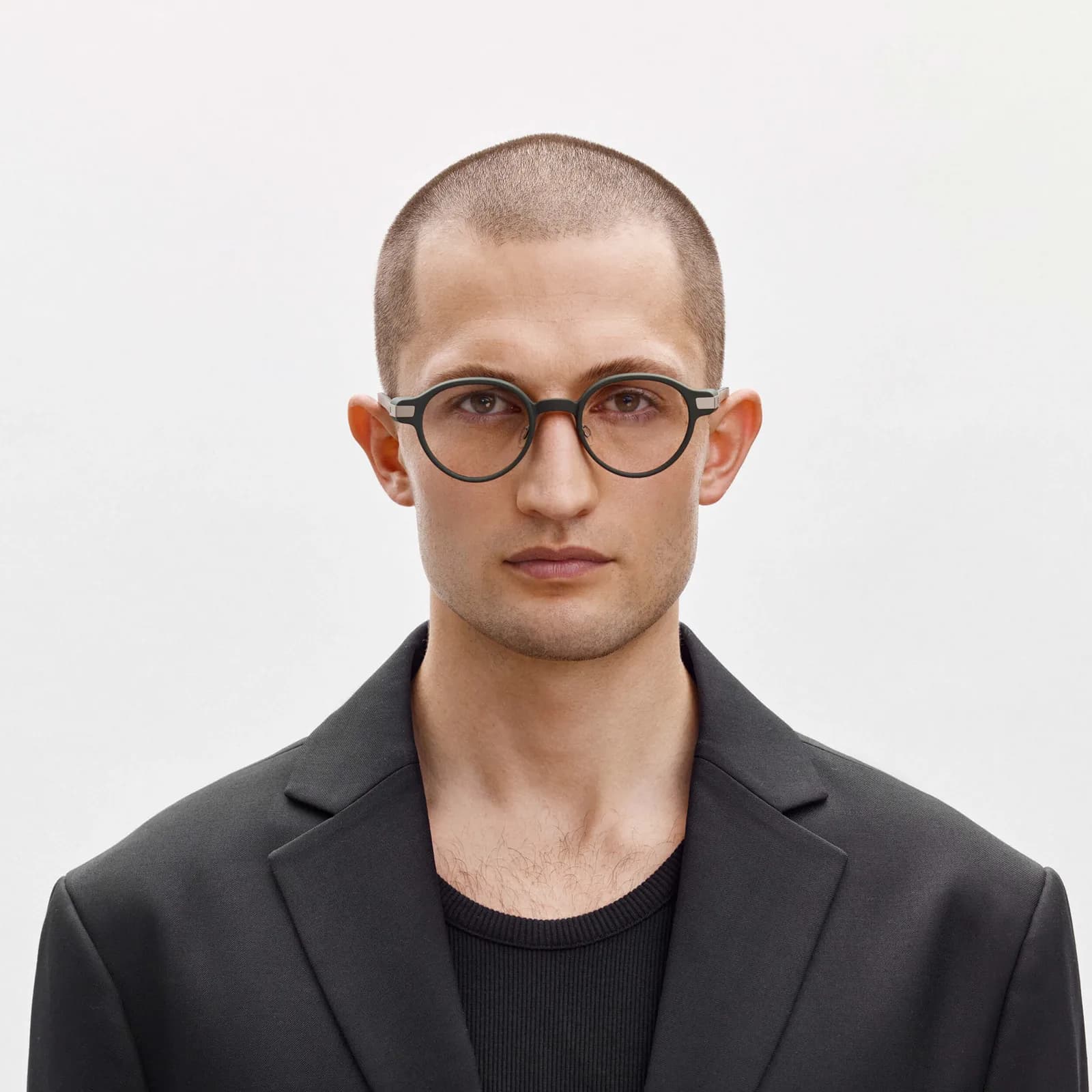 Gafas inteligentes Even Realities G1 puestas en un hombre de cabeza rapada, montura redonda verde con cristales oscurecidos, fondo blanco liso.