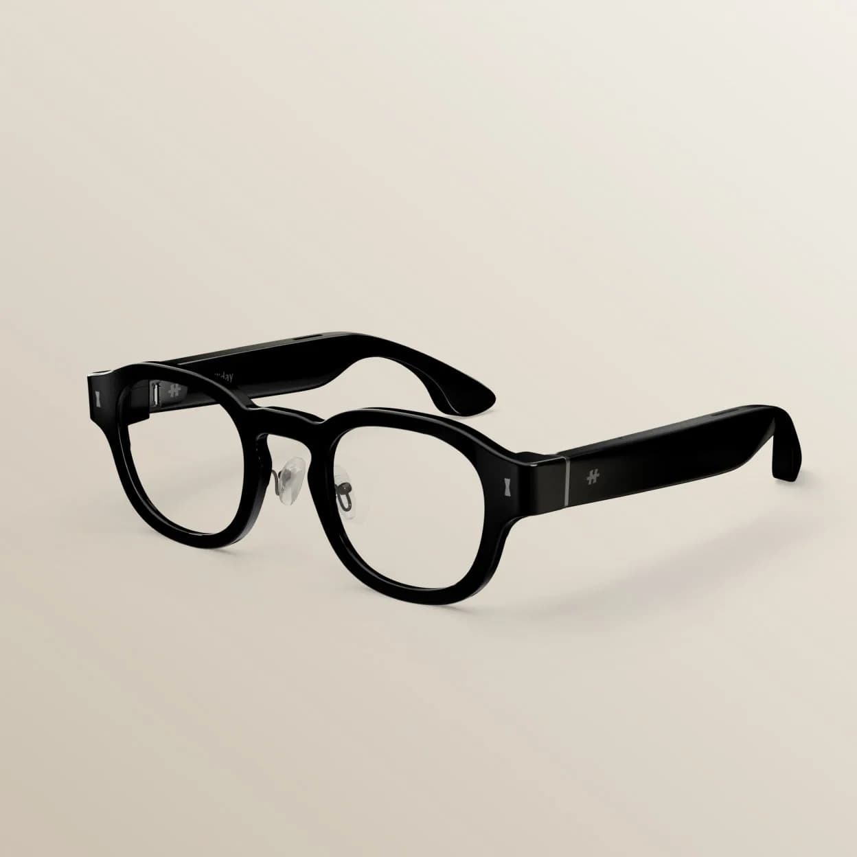 Gafas inteligentes Halliday G2 en negro, vista en ángulo de la montura redonda mostrando la bisagra de la patilla y el logotipo, fondo beige.