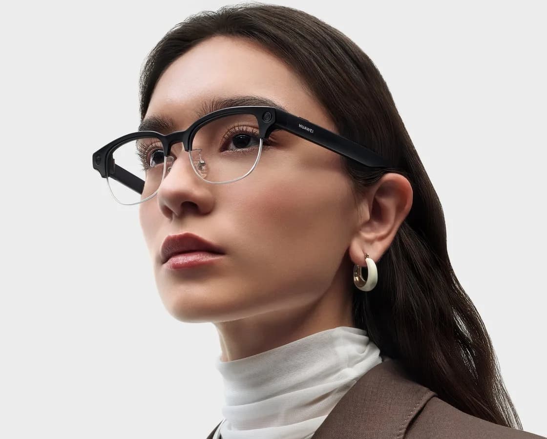 Una mujer lleva las Huawei AI Glasses en negro, de perfil sobre fondo gris: montura clubmaster de aro grueso arriba y mitad inferior sin aro, la cámara en el ángulo externo de la lente derecha y HUAWEI escrito a lo largo de la patilla.
