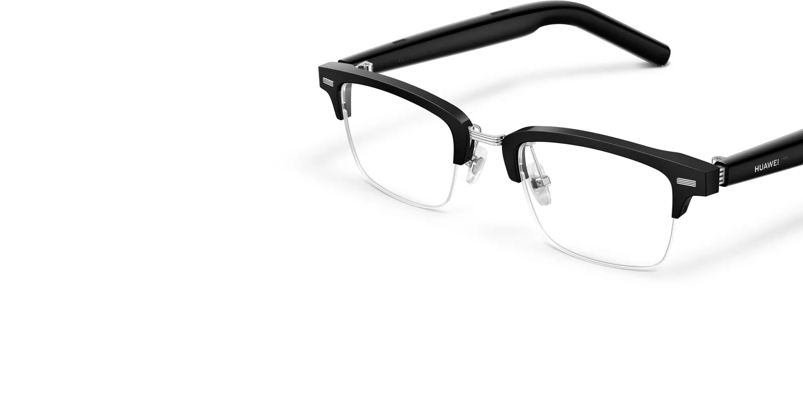 Gafas HUAWEI Eyewear 2 en primer plano, barra superior negra sobre aro inferior cromado, bisagra plateada, HUAWEI en la patilla, ángulo desde abajo.