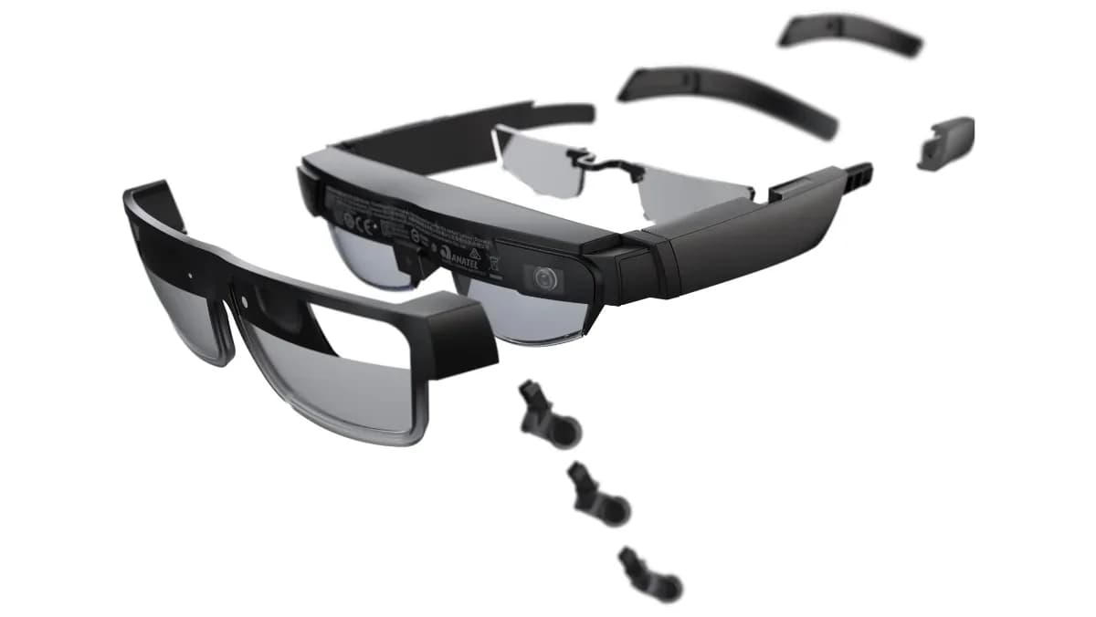Lenovo ThinkReality A3 glasses in black, worn by a woman viewing three floating virtual monitors above an open laptop on a desk.