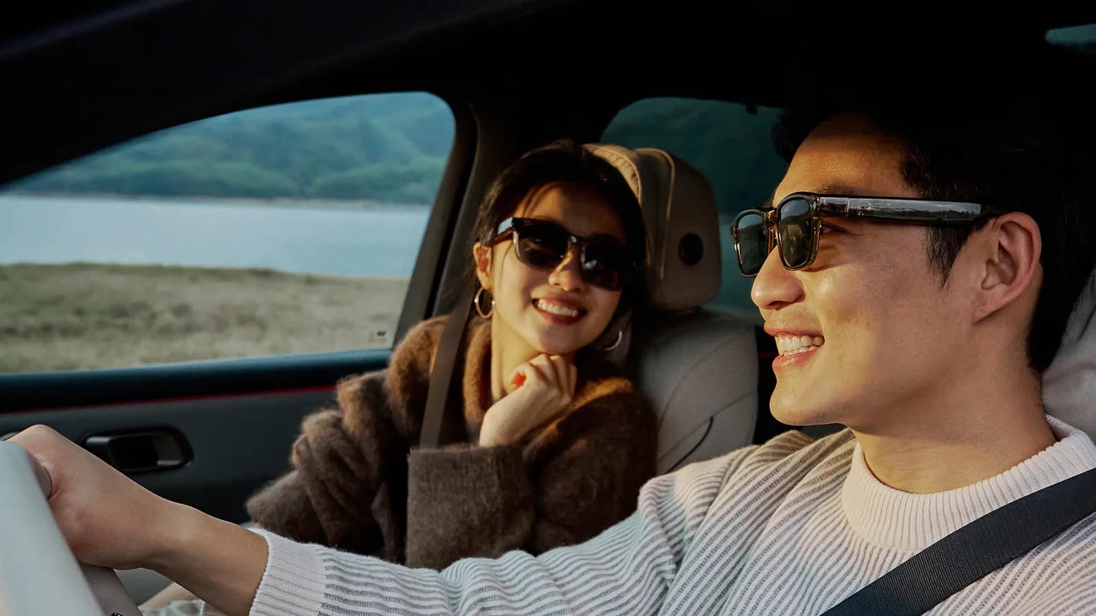 Óculos inteligentes Li Auto Livis, em tartaruga âmbar, usados por um homem dirigindo um carro, com armação retangular grossa e lentes escuras.