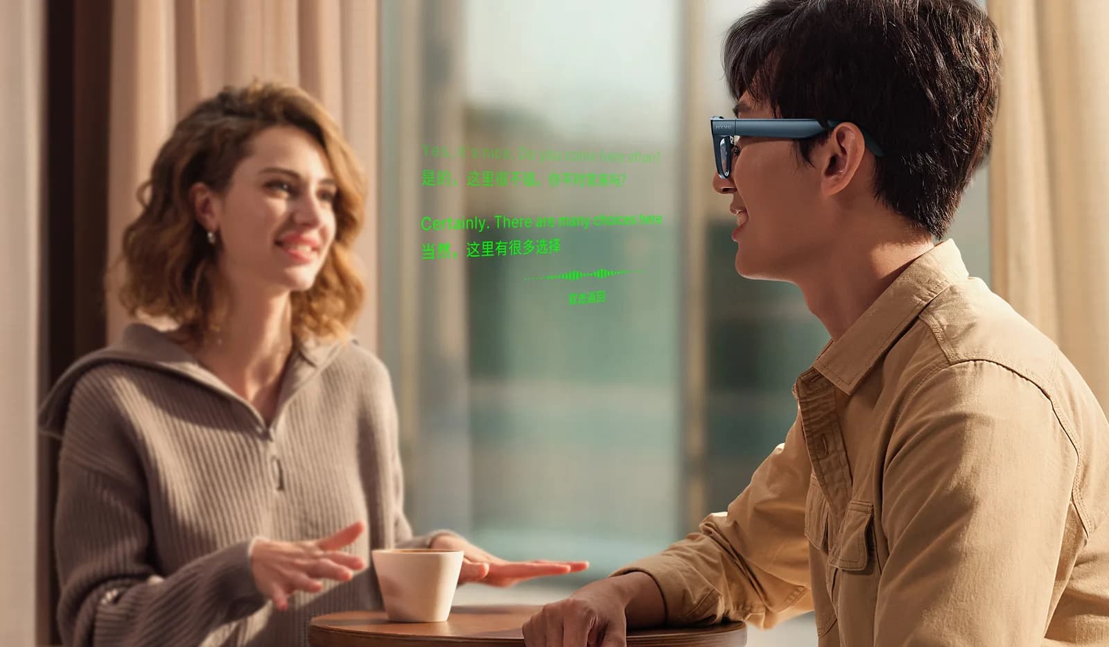 Gafas Meizu MYVU en gris metalizado en el rostro de un hombre, de perfil en una mesa de café frente a una mujer.