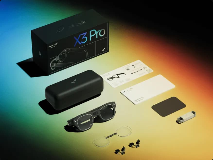Óculos de RA RayNeo X3 Pro em preto, dispostos com a caixa, o estojo rígido, o pano de limpeza e um clipe de lente na mesa.