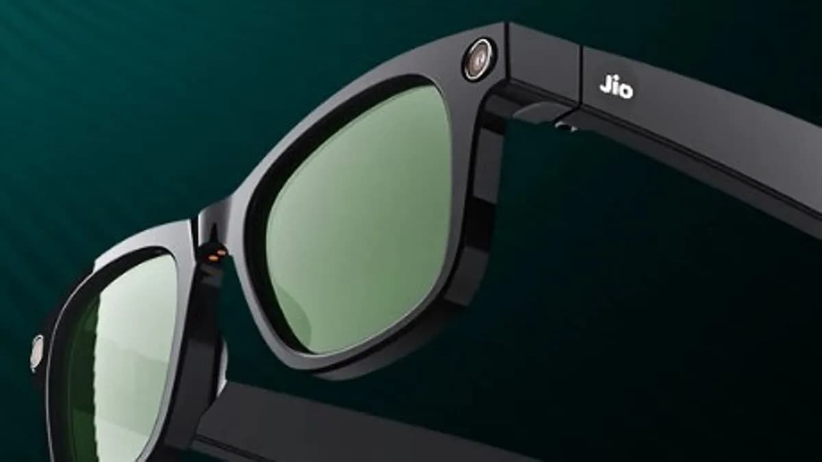 Gafas JioFrames en negro con lente verdosa, primer plano mostrando la cámara en el aro y el logo Jio en la patilla.