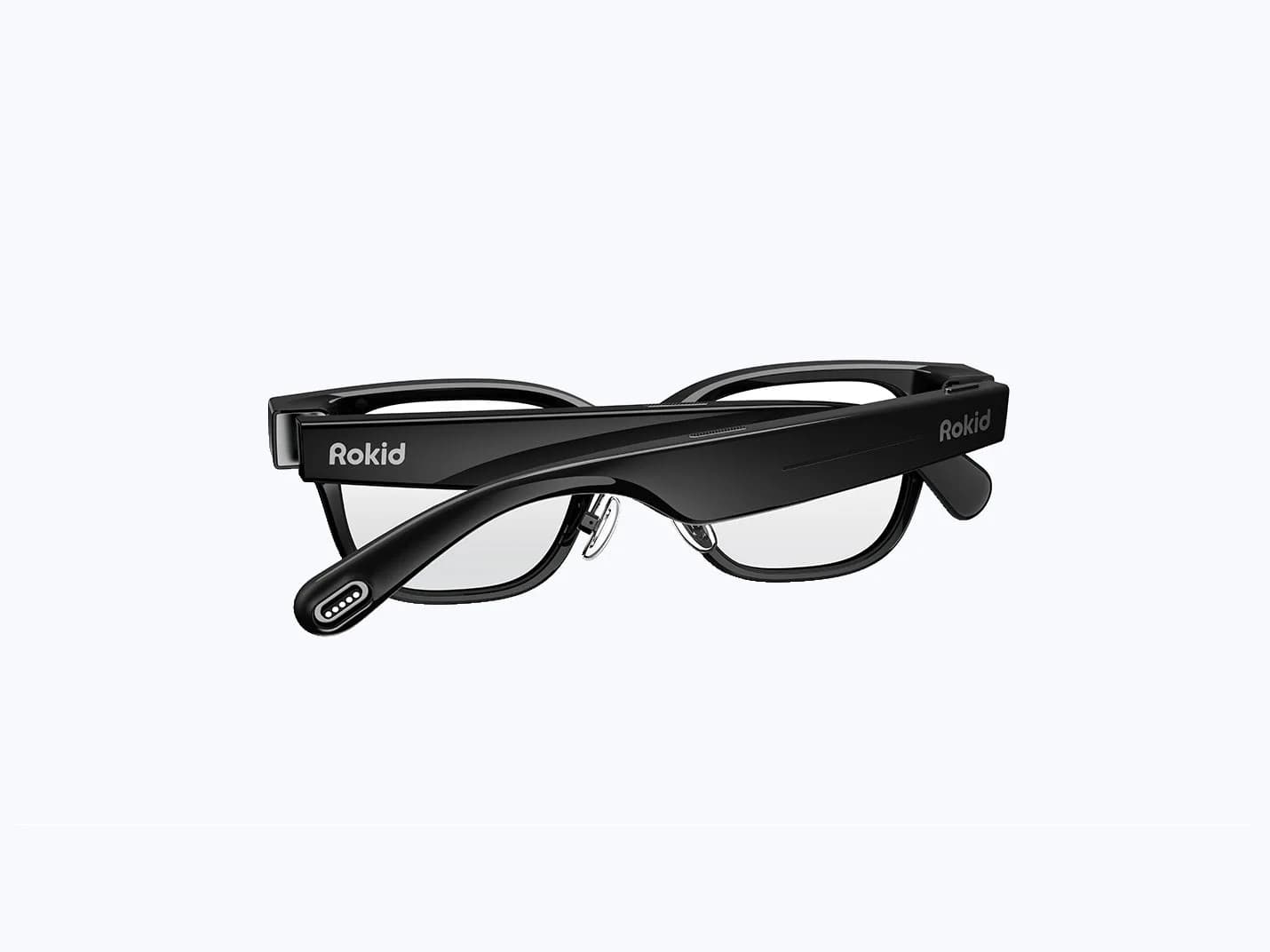 Rokid AI Glasses Style in black, seen from behind, showing the Rokid print on both temples, nose pads, and charging pins on the left tip.