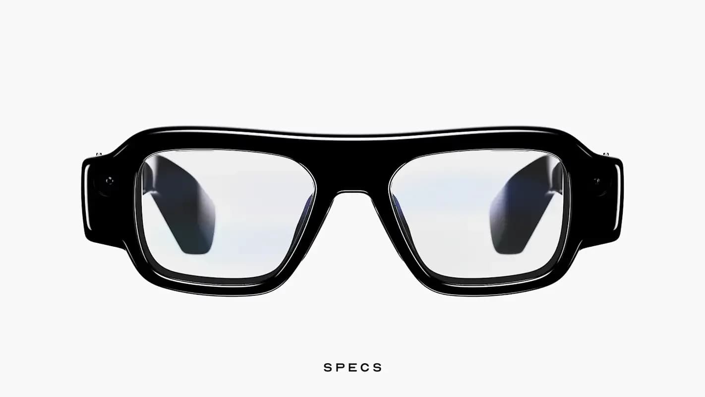 Snap Specs AR glasses in black with a thick rectangular frame, clear lenses, and small cameras built into both hinge corners, front view.