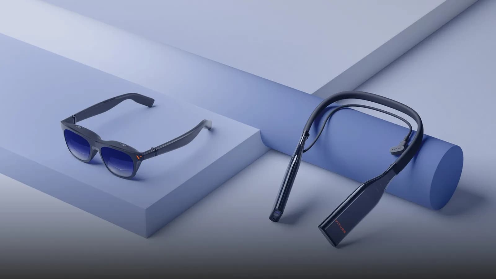 VITURE Pro AR glasses in dark gray with blue gradient lenses, resting on a blue block beside a black VITURE neckband accessory, on a blue geometric background.