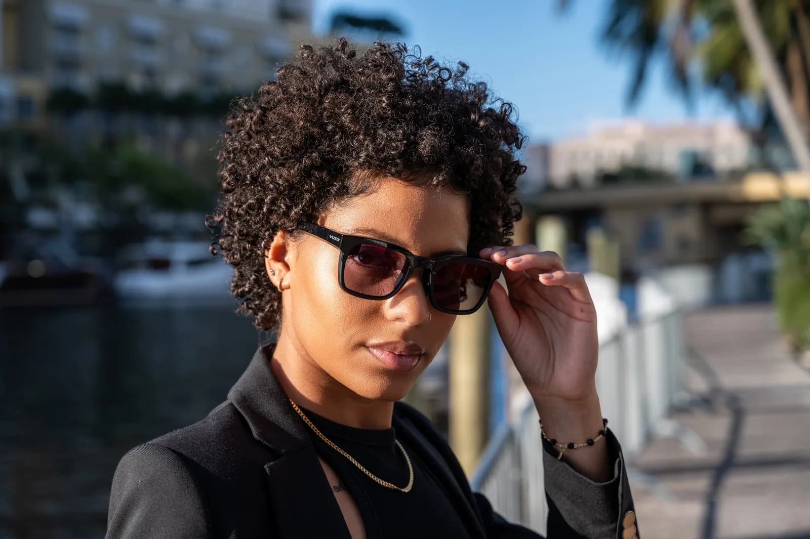Gafas Vuzix Z100 en negro, usadas por una mujer al aire libre cerca de un puerto, con lentes cuadrados oscuros.