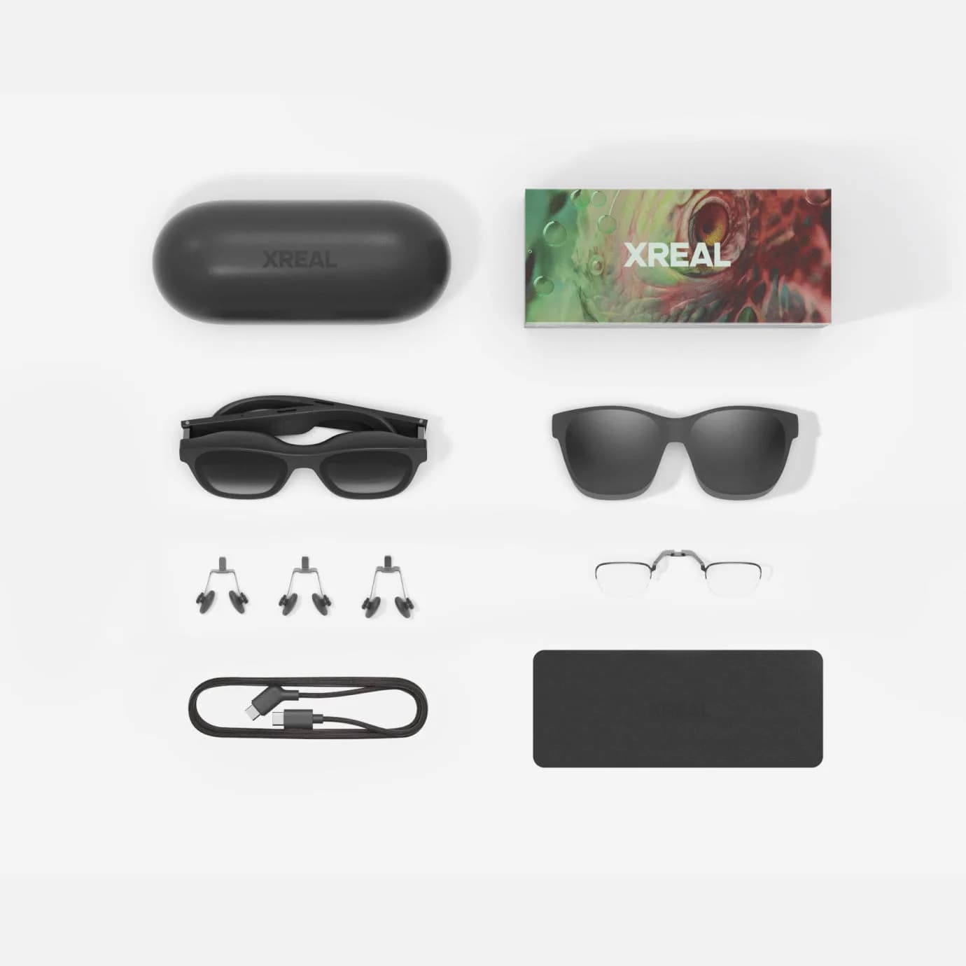 XREAL Air 2 Pro配件平铺：折叠盒、备用鼻托、USB-C数据线和金属近视镜架。