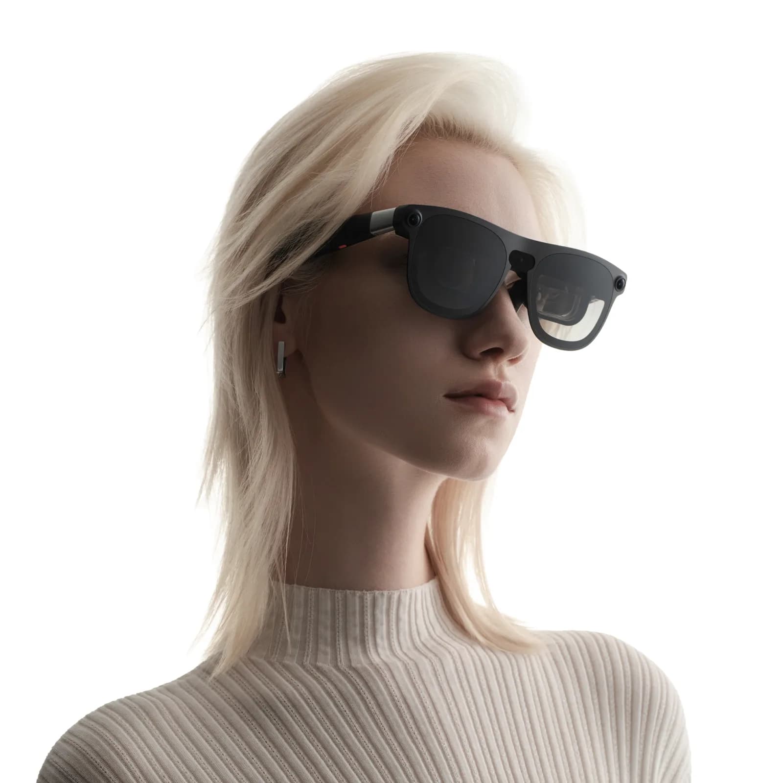 XREAL Aura glasses in black on a woman's face, side angle, with a small camera visible above the left lens and a cream sweater.