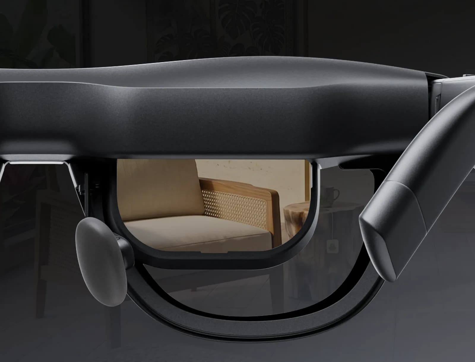 Close-up through a XREAL Aura lens in black, showing a chair and a room seen clearly through the transparent glass.