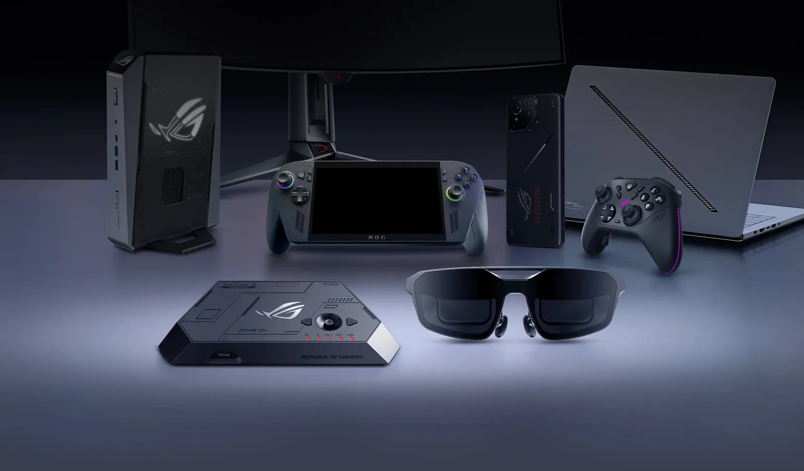 Gafas ROG XREAL R1 negras en primer plano frente a otros dispositivos ASUS ROG: una consola portátil, un teléfono, un portátil y un mando.