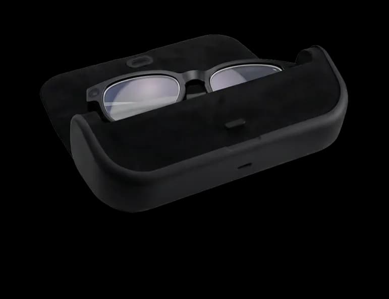 Mentra Live glasses folded inside their open black charging case, with the camera lens visible on the frame.