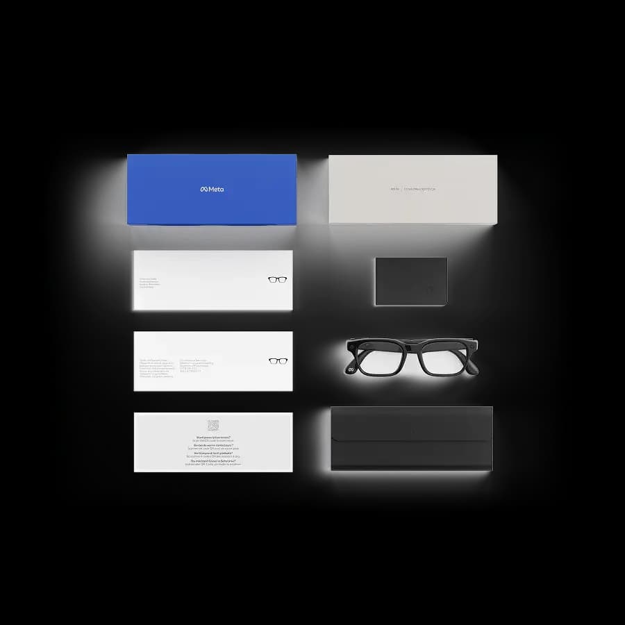 Meta Glasses unboxed flat lay with a blue retail box, instruction leaflets, a black charging card, and a black folded case.