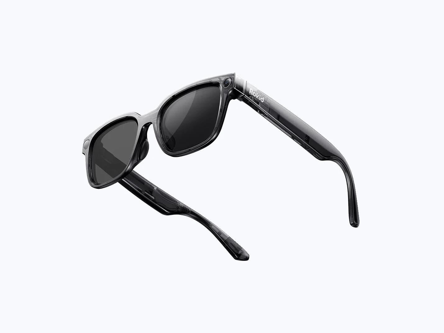 Rokid AI Glasses Style in translucent smoke gray, folded at an angle against a plain background, with a small camera near the temple hinge.